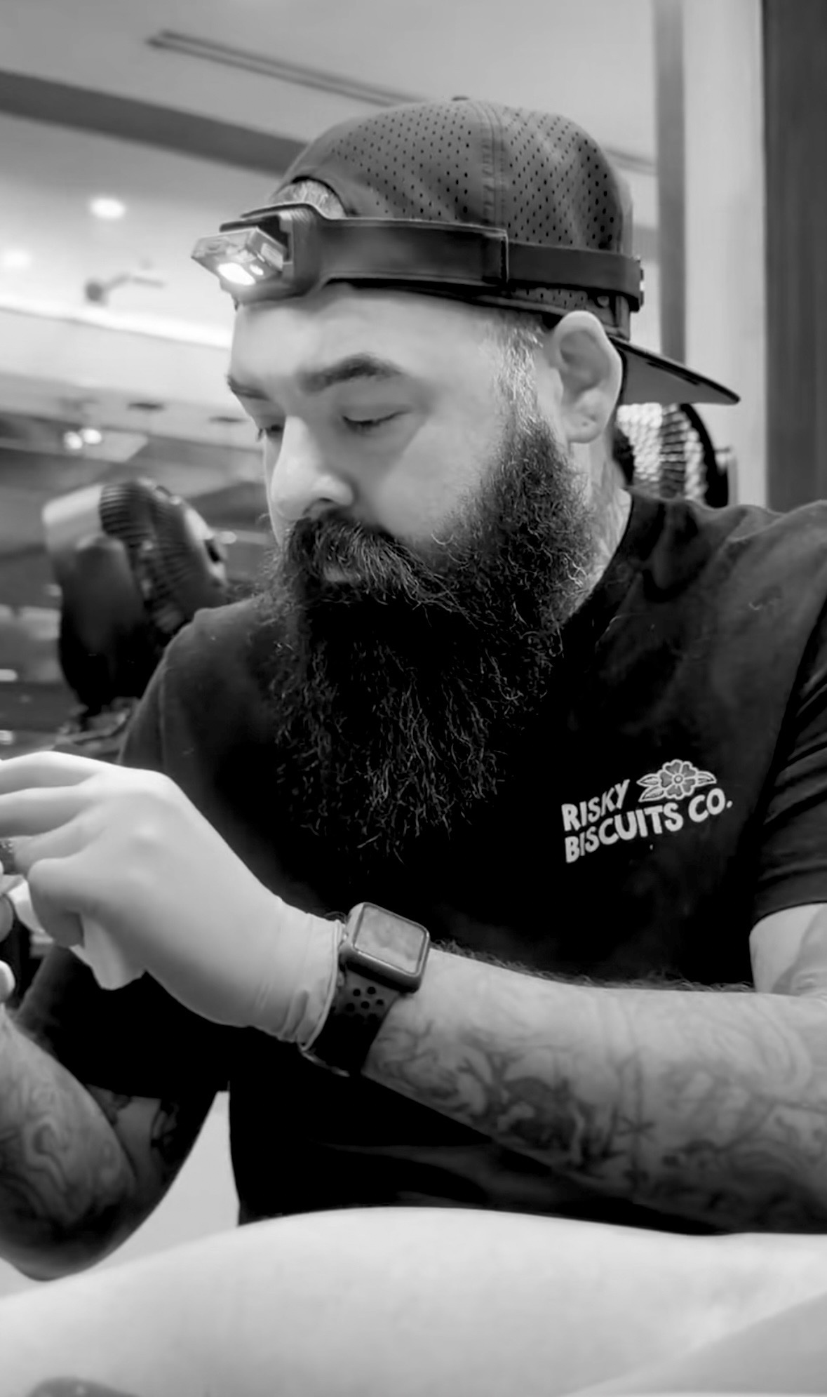Joe Castillo tattooing, wearing a headlamp